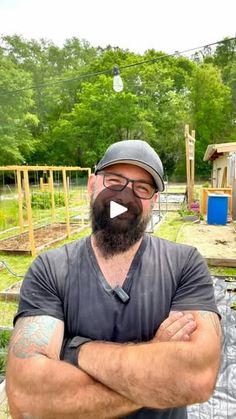 a man standing in front of a vegetable garden with his arms crossed and looking at the camera