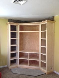 an empty wooden bookcase in a room with yellow walls and carpeted flooring