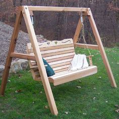 a wooden swing set in the grass with a bag on it's back end