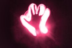 a person holding their hand up in the air with light shining on them at night