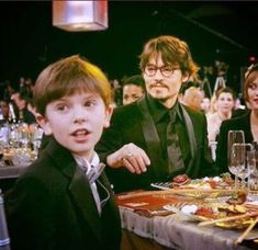 two children and an adult sitting at a table in front of people with glasses on it