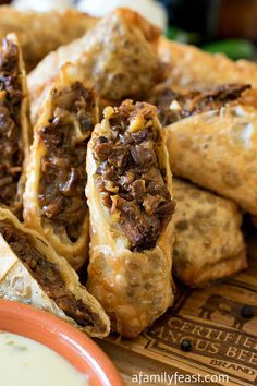 several pastries are piled on top of each other in a plate with dipping sauce