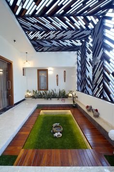 the inside of a modern house with grass and plants in the yard, along with wooden flooring