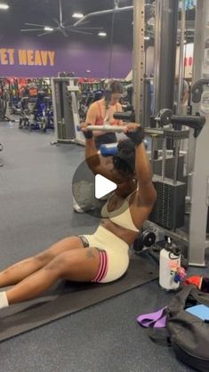 a woman laying on the ground in a gym doing an exercise with her legs up