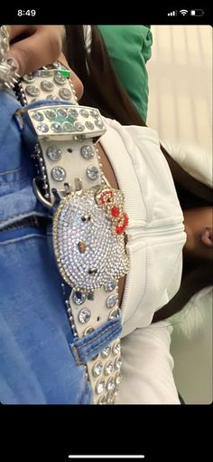 the belt is adorned with jewels and beads on it's side, while someone holds onto her jeans