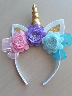 a unicorn headband with flowers and a gold horn on the top, sitting on a table