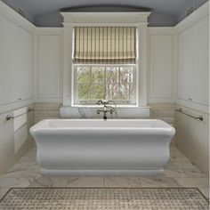 a white bath tub sitting under a window in a bathroom