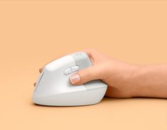 a person's hand holding a computer mouse on top of a table with a brown background