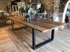 a wooden table sitting on top of a hard wood floor next to a brick wall