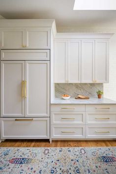 a kitchen with white cabinets and an area rug in front of the counter top that has a potted plant on it