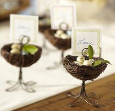 small bird's nest centerpieces with place cards in them on a table