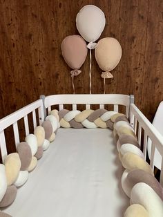 a crib with pillows and balloons hanging on the wall