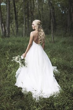 a woman in a wedding dress standing in the woods