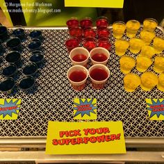 a table topped with cups and trays filled with drinks next to a sign that says pick your super power