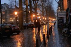 people are walking down the street in the rain