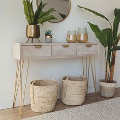 a table with some plants and baskets on top of it next to a mirror in a room