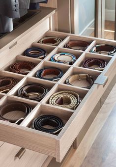 an open drawer with many belts in it