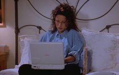 a woman sitting on her bed using a laptop computer