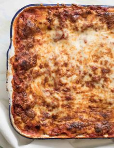 a casserole dish with meat and cheese in it sitting on a white cloth