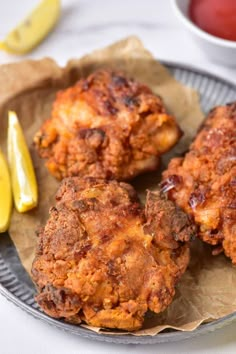 three fried food items on a plate with lemons and ketchup in the background