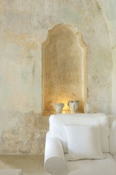 a white couch sitting in front of a wall with two vases on top of it