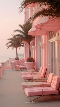 a row of pink lounge chairs sitting on the side of a building next to palm trees