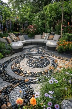 an outdoor seating area with rocks and flowers on the ground, surrounded by greenery