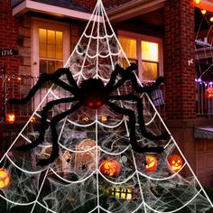 a decorated christmas tree in front of a house with spider webs and pumpkins