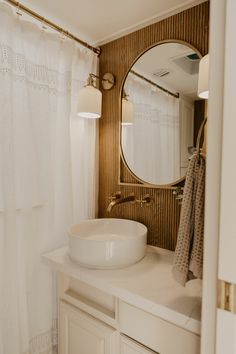 a white sink sitting under a bathroom mirror next to a shower curtain in a bathroom