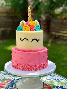 a birthday cake decorated with flowers and an unicorn face