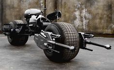 an unusual motorcycle is parked in front of a concrete wall with no wheels on it