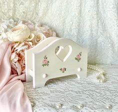 a white bed frame with pink roses and pearls on the table next to it is a bouquet of flowers