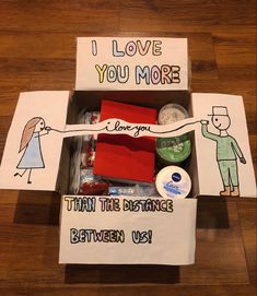 an open box with various items inside on a wooden floor next to a sign that says, i love you more than the distance between us