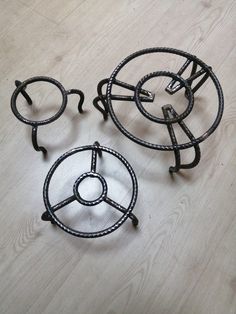 two metal objects sitting on top of a wooden floor next to each other in the shape of circles