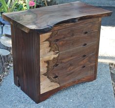 a wooden dresser sitting on top of a cement floor next to a flower potted plant