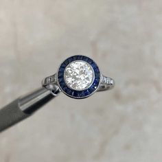 a diamond and blue sapphire ring sitting on top of a pen