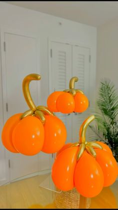 three orange balloons sitting on top of a table in the shape of pumpkins with gold stems