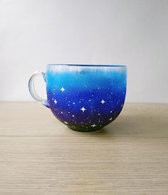 a blue and white cup sitting on top of a wooden table with stars painted on it