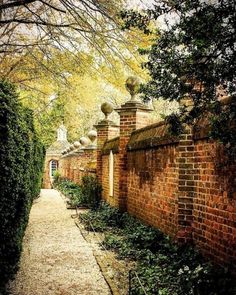 an old brick wall and walkway in the middle of a garden