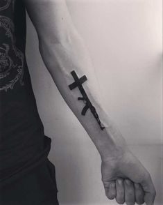 a person with a tattoo on their arm holding a cross and two swords in the other hand