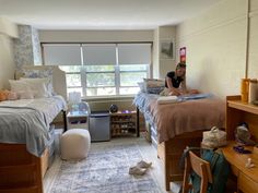 a woman sitting on top of a bed in a bedroom next to two twin beds