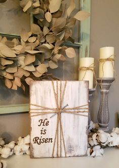 a wooden box with a message on it sitting next to cotton flowers and a candle