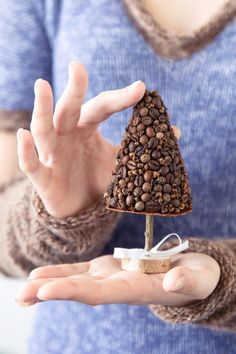 a person holding a small christmas tree made out of coffee beans in their hands,