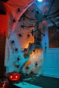 halloween decorations in front of a house with spider webs and pumpkins on the door