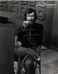 an old photo of a man sitting in a chair with his hand on his chin