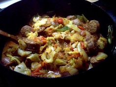 a skillet filled with meat and vegetables on top of a stove