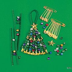 a christmas tree made out of beads and other items on a green surface with gold pins