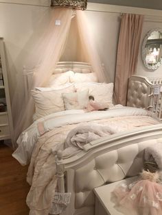 a white bed sitting in a bedroom next to a dresser and mirror on the wall