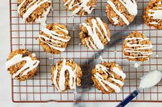 cookies with icing on a cooling rack next to a spoon and glass of milk