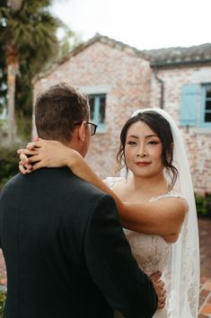 a bride and groom standing in front of a brick building